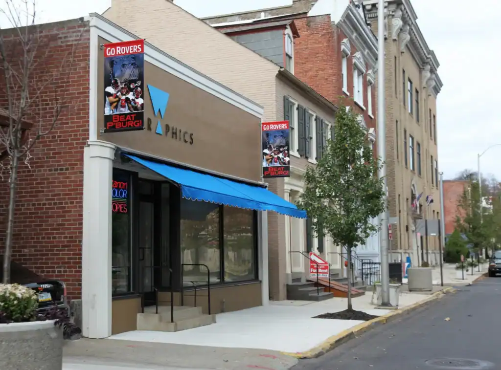 exterior photo of W Grahics showing a blue awning and a custom printed Easton flag
