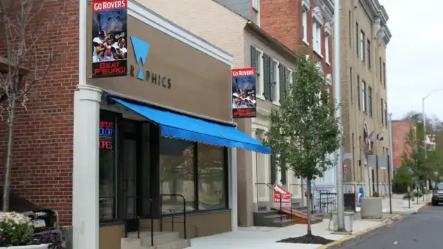 exterior photo of W Grahics showing a blue awning and a custom printed Easton flag