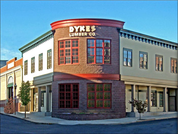 Modern commercial building for Dykes Lumber Co. in Easton, featuring a distinctive rounded corner with large red-framed windows, situated on a city street with trees and clear blue sky.