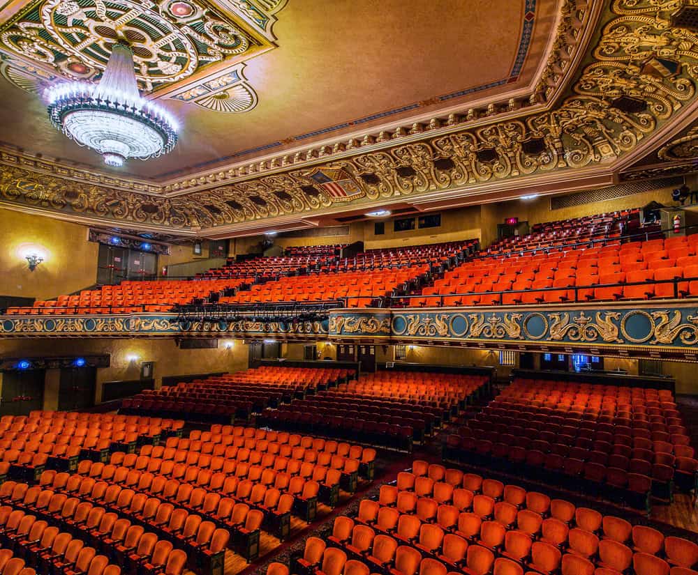 Interior view of the historic State Theatre Center for the Arts with ornate ceiling, grand chandelier, and rows of red seats for performances.