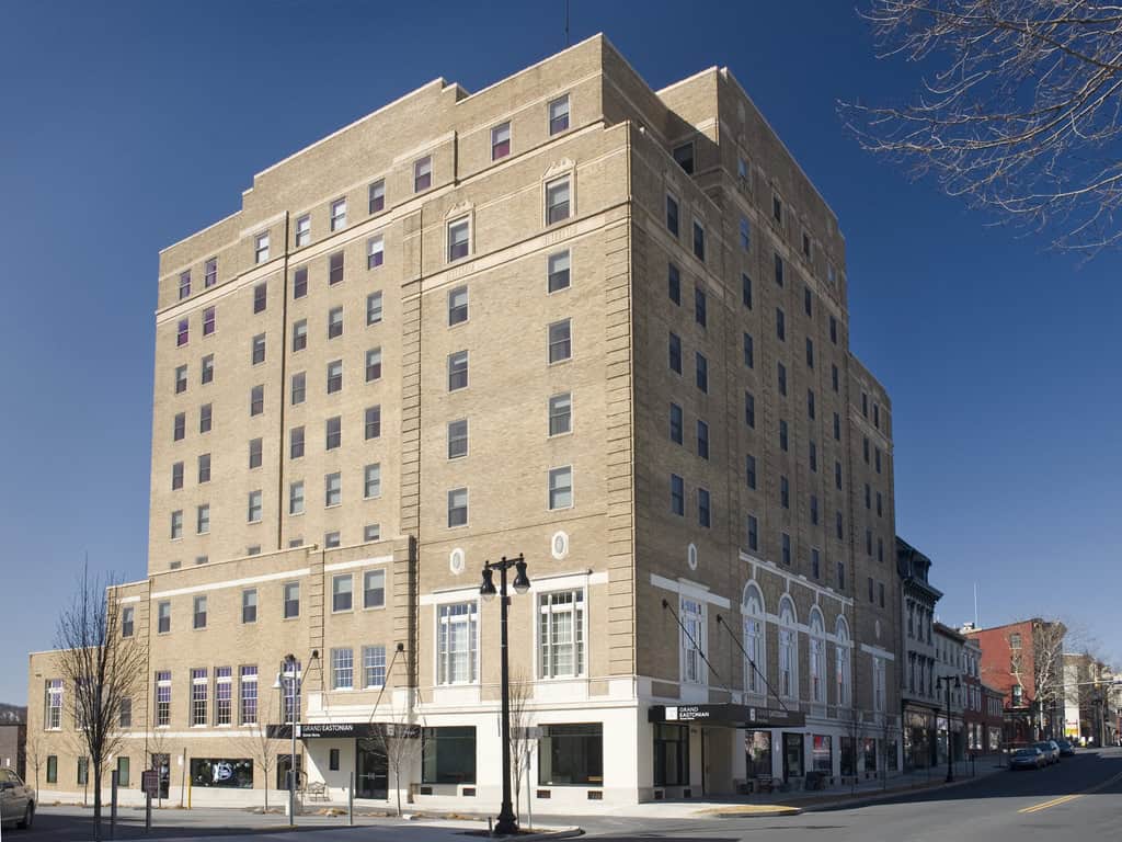 Exterior view of the Grand Eastonian Hotel & Suites, a large multi-story brick building in Easton, Pennsylvania, under a clear blue sky.