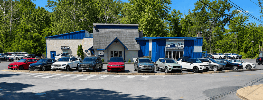 Exterior view of Easton Post automotive service center with multiple cars parked in front, surrounded by green trees and a clear blue sky.