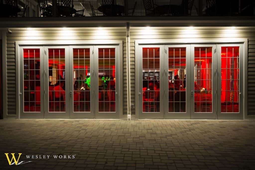 Brightly lit restaurant with large glass windows showing red interior decor and patrons dining inside at night.