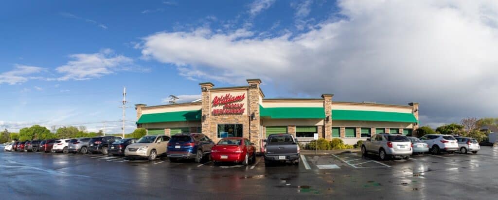 Exterior view of Williams Restaurant with a large parking lot and multiple cars on a cloudy day.