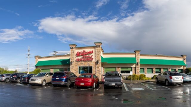 Exterior view of Williams Restaurant with a large parking lot and multiple cars on a cloudy day.