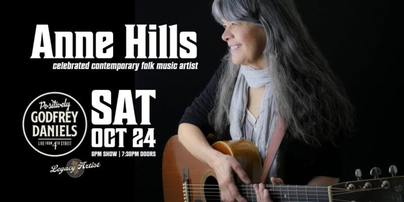 Anne Hills, a celebrated folk artist, performing with her guitar at a concert promoting her latest album, showcasing heartfelt vocals and contemporary folk music.
