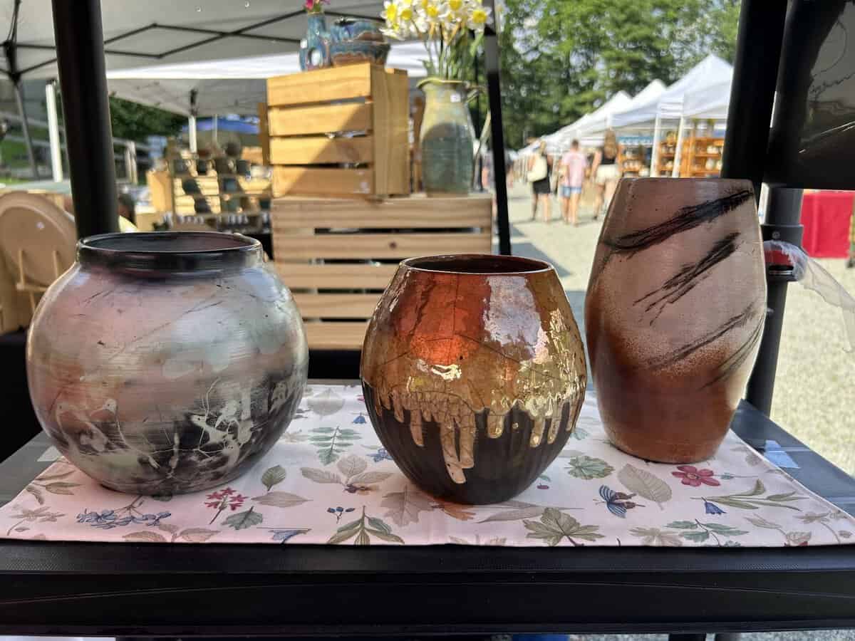 Three handcrafted pottery vases displayed on a table at Stahl’s Pottery Fall Festival 2026 with outdoor market tents in the background.