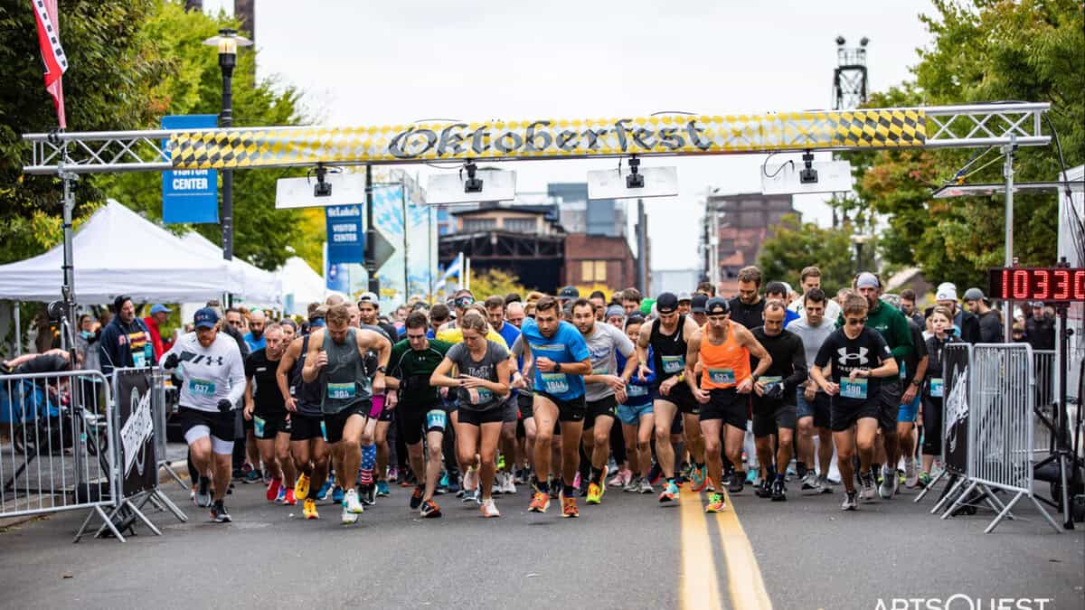 Runners at the start line of the Yuengling Oktoberfest 5K race in Easton, Pennsylvania, with a large crowd and festive atmosphere.