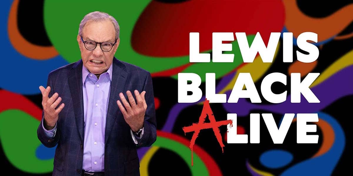 Lewis Black performing live on stage with a colorful abstract background, emphasizing his comedic style and energetic presence.