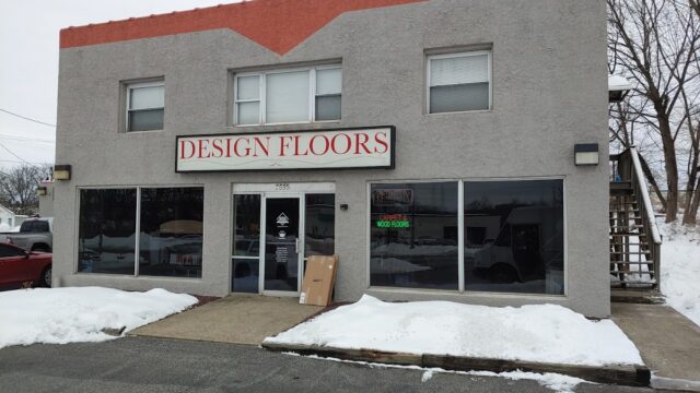 Exterior view of Design Floors LV storefront with large glass windows and a sign, snow on the ground, in a commercial area.